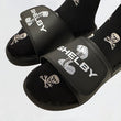 Load image into Gallery viewer, Close up of two feet wearing Shelby sandals and skull-and-wrench graphic socks