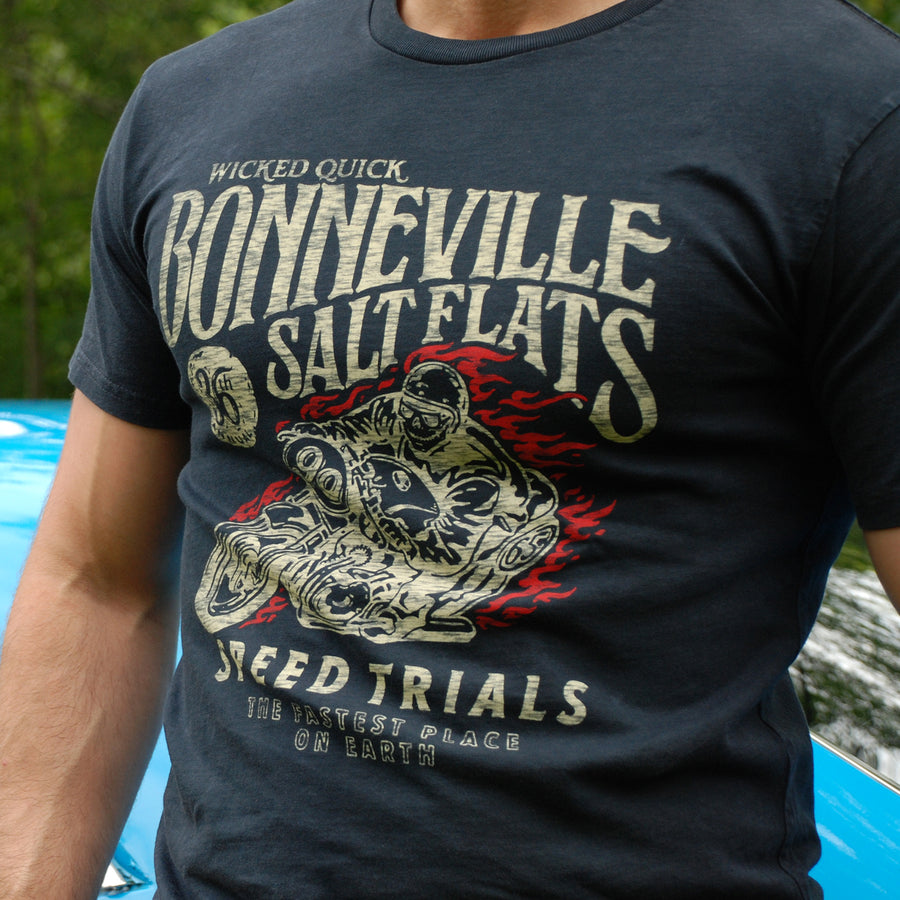 Man wearing a Bonneville Salt Flats black graphic t shirt standing in front of a race car