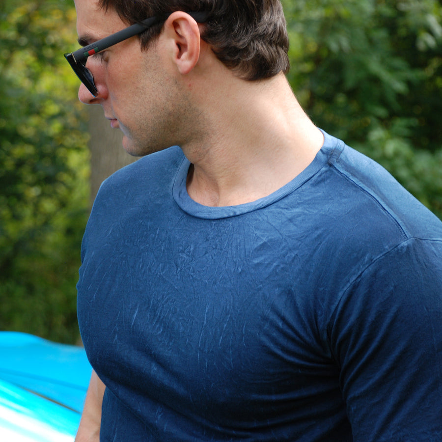 Man wearing a blue crew neck t-shirt and sunglasses looking at a Ford Shelby car