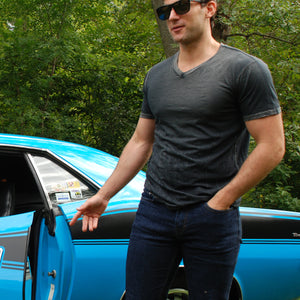 Man wearing a charcoal v neck t shirt standing in front of a Ford Shelby Mustang